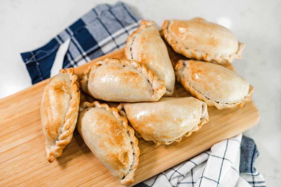 Versgebakken empanadas opgestapeld op een houten snijplank